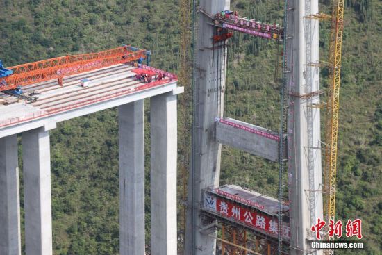11月22日，峰林特大橋4號主塔中橫梁正在吊裝。當(dāng)日，隨著1470噸裝配化預(yù)制中橫梁提升到位，貴州省黔西南布依族苗族自治州興義環(huán)城高速公路峰林特大橋4號主塔中橫梁成功吊裝，由此刷新了山區(qū)峽谷橋梁預(yù)制吊裝混凝土構(gòu)件重量世界記錄。峰林特大橋是屬全線控制性工程。大橋跨越馬嶺河峽谷，全長1163米，主跨采用550米懸索橋，橋面離谷底364.2米，是中國山區(qū)第一座大跨徑鋼混疊合梁懸索橋。中新社記者 瞿宏倫 攝