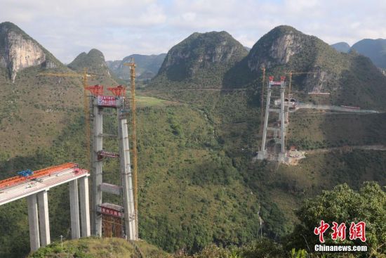 11月22日，正在建設(shè)中的峰林特大橋。當(dāng)日，隨著1470噸裝配化預(yù)制中橫梁提升到位，貴州省黔西南布依族苗族自治州興義環(huán)城高速公路峰林特大橋4號主塔中橫梁成功吊裝，由此刷新了山區(qū)峽谷橋梁預(yù)制吊裝混凝土構(gòu)件重量世界記錄。峰林特大橋是屬全線控制性工程。大橋跨越馬嶺河峽谷，全長1163米，主跨采用550米懸索橋，橋面離谷底364.2米，是中國山區(qū)第一座大跨徑鋼混疊合梁懸索橋。中新社記者 瞿宏倫 攝