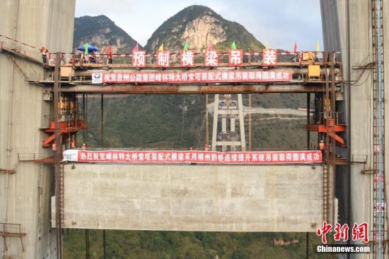 11月22日，隨著1470噸裝配化預(yù)制中橫梁提升到位，貴州省黔西南布依族苗族自治州興義環(huán)城高速公路峰林特大橋4號主塔中橫梁成功吊裝，由此刷新了山區(qū)峽谷橋梁預(yù)制吊裝混凝土構(gòu)件重量世界記錄。峰林特大橋是屬全線控制性工程。大橋跨越馬嶺河峽谷，全長1163米，主跨采用550米懸索橋，橋面離谷底364.2米，是中國山區(qū)第一座大跨徑鋼混疊合梁懸索橋。中新社記者 瞿宏倫 攝